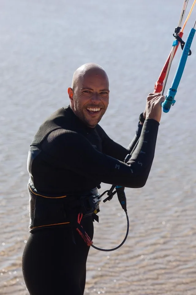 Floris Dielen, smiling and holding the kite control bar while kitesurfing